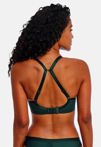 Dunkelgrüner Sport-BH mit strukturierter Oberfläche, verstellbaren Trägern, die einen Racerback-Stil bilden, und einem schmalen elastischen Band am Saum.