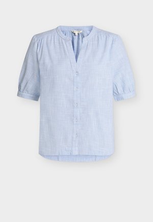 Lichtblauwe blouse met korte mouwen en een subtiel ruitpatroon, ronde hals met kleine V-uitstulping, knoopsluiting aan de voorkant en licht geplooide schouders en mouwen.