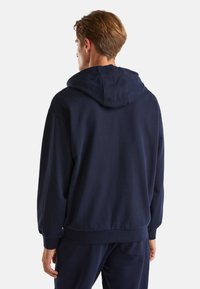 Námořnická modrá mikina s kapucí vyrobená z měkké tkaniny, s volným střihem, šňůrkovou kapucí a žebrovanými manžetami a lemem.