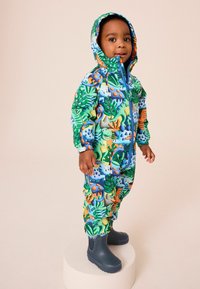 Colorful children's rain suit featuring a vibrant dinosaur and foliage print, with a hood, elastic cuffs, and a front zipper. Paired with blue boots.