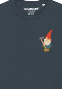T-shirt en coton bleu foncé avec un motif représentant un gnome portant un chapeau rouge, un pantalon vert et une fourche, positionné sur le côté gauche.