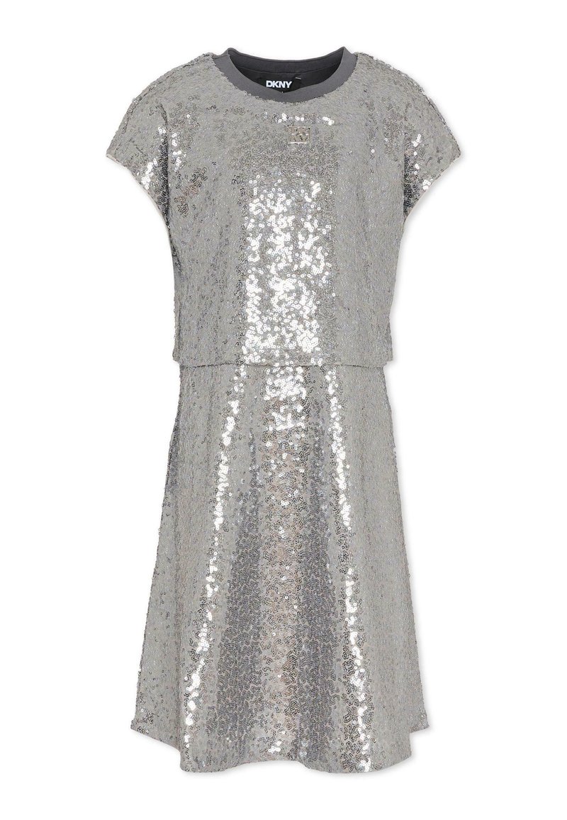 Srebrna sukienka z cekinami, z okrągłym dekoltem i krótkimi rękawami. Górna i dolna część są oddzielone poziomą linią na wysokości talii.