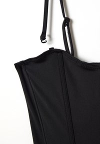 Zwarte strapless top met een getailleerde bustier, een soepele stoftextuur en gestructureerde naden langs de zijkanten voor een gepolijste uitstraling.
