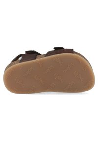 Bruine leren sandaal met twee verstelbare banden, voorzien van een gestructureerde bruine rubberen zool met het "kipling" patroon.