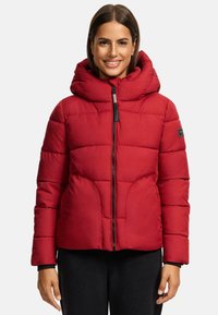 Red padded jacket with a large hood, front zipper, and side pockets. Features a quilted design and a black logo patch on the sleeve.