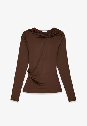Top marrón de manga larga con detalle de nudo retorcido en el cuello y el lado, forma ajustada, textura lisa sobre un fondo blanco.