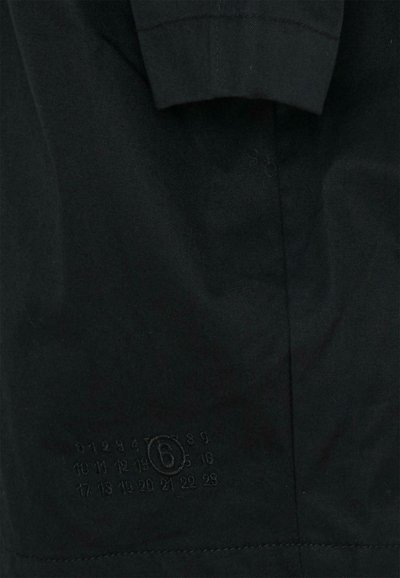 Czarny bawełniany T-shirt z okrągłym dekoltem, krótkimi rękawami i wytłaczanym logo z cyframi i literą na dole po prawej stronie.