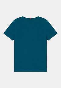 Teal-kottinen T-paita, jossa on lyhyet hihat ja V-pääntie. Minimalistinen tyyli; ei näkyviä kuvioita tai yksityiskohtia. Sujuva pinta.