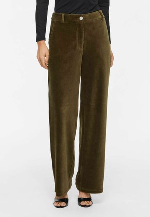 Woman wearing olive green wide-leg corduroy pants with button closure and black open-toe heels against white background.