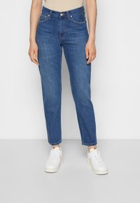 Light blue high-waisted jeans, straight-leg design, classic five-pocket styling, contrast stitching, cuffed hem, paired with white sneakers.
