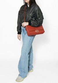 Rode leren schoudertas met een voorflap en metalen hardware. De tas heeft een rechthoekige vorm en een gestructureerde afwerking.