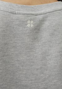 Grå bomull t-skjorte med en subtil ribbet tekstur og en liten brodert blomsterdesign ved bakhalsen.