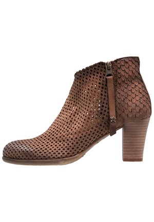 Bottine en cuir marron avec avant perforé, zone du talon texturée, fermeture éclair latérale, tirette en forme d'étoile et talon bloc empilé.