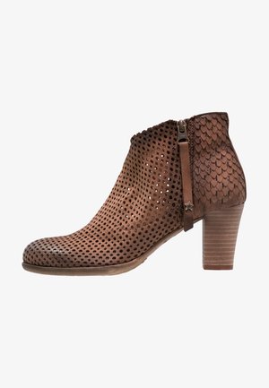 Bottine en cuir marron avec avant perforé, zone du talon texturée, fermeture éclair latérale, tirette en forme d'étoile et talon bloc empilé.