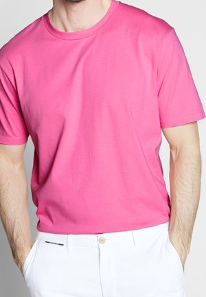 Roze katoenen t-shirt met korte mouwen en een ronde halslijn, gecombineerd met witte broeken met knoopsluiting en een strakke zakdetail.