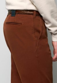 Bruine katoenen broeken met een gestructureerde afwerking, voorzien van een geweven bruine riem en een achterzak met een subtiele naaddetail.