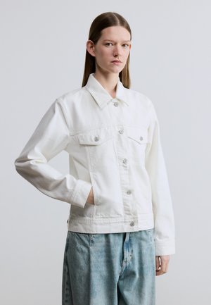 Witte spijkerjasje met knoopsluiting aan de voorkant, klassieke kraag en twee borstzakken. Heeft een losse pasvorm en lange mouwen.