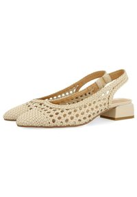 Zapatos de tacón bajo tipo slingback en color beis, con punta afilada y diseño con cortes. Fabricados en un material texturizado con un acabado natural.