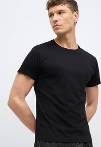 Μαύρο κοντομάνικο μπλουζάκι με στρογγυλή λαιμόκοψη, κατασκευασμένο από απαλό βαμβακερό ύφασμα. Λείο υφασμάτινο, εφαρμοστή γραμμή και μινιμαλιστικές λεπτομέρειες σχεδίασης.