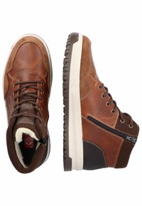 Bottes en cuir et en daim marron avec un col rembourré, des lacets, une fermeture éclair sur le côté et une semelle en caoutchouc ; elles présentent des panneaux de couleurs contrastantes et des coutures.