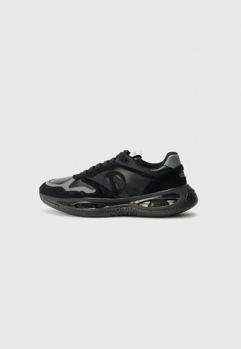 Sorte og grå sneakers med en blanding av semsket skinn og syntetiske materialer, rund tå, teksturert mellomsåle og synlige luftdempingselementer.