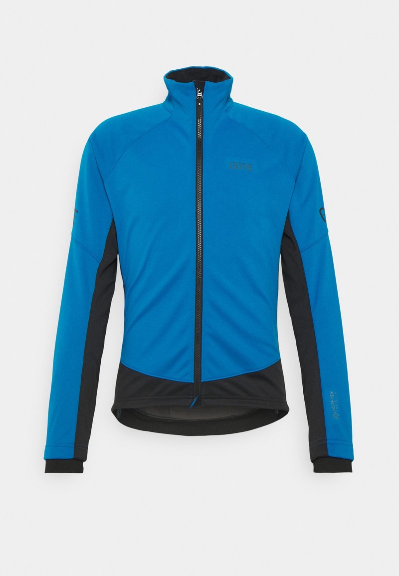 Veste de sport bleue et noire avec un col haut, fermeture éclair intégrale et manches longues. Présente une texture lisse et un logo sur la poitrine et la manche.