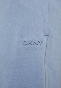 Tecido de malha azul claro com um acabamento texturizado; inclui um logótipo bordado da DKNY de um lado. Design simples com um corte descontraído.