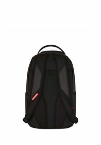 Zaino nero con spallacci ergonomici imbottiti e pannelli testurizzati, dotato di maniglia superiore e di un accento rosso nel logo. Design minimale, forma slanciata.