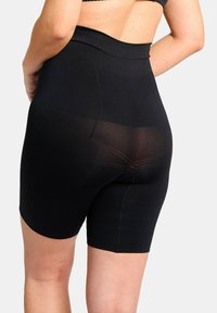 Zwarte high-waisted shapeshorts met een gestructureerde afwerking, met een doorschijnend paneel aan de achterkant, ontworpen voor ondersteuning en dekking.
