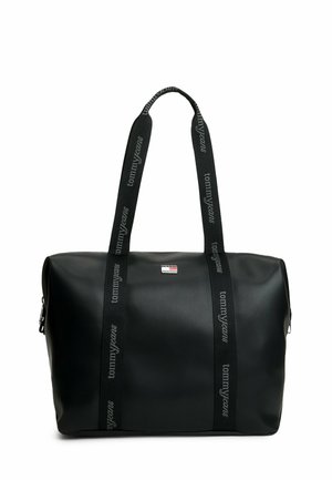 Czarna torba typu tote z długimi czarnymi uchwytami z nadrukiem "tommyjeans" oraz mała naszywka z logo Tommy Jeans z przodu na środku.
