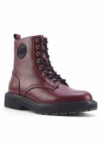 Stivali stringati in pelle bordeaux con punta arrotondata, suola in gomma nera e patch rotondo con logo sul lato. Caratterizzati da occhielli in metallo e finitura testurizzata.