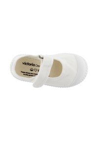 Zapato Mary Jane de lona blanca con una correa de velcro, suela de goma texturada y logo de la marca visible en la plantilla. Diseño limpio y minimalista.