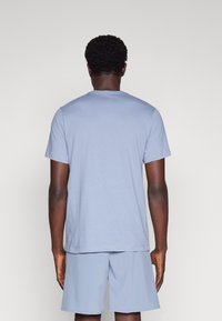 Camiseta de algodón azul claro con mangas cortas, cuello redondo y un corte relajado, combinada con pantalones cortos azul claro a juego.