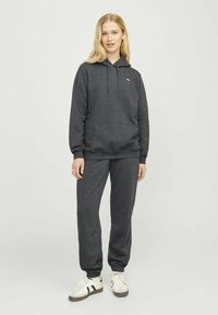 Mørkegrå hettegenser med snøring og frontlomme, kombinert med matchende joggebukser. Stoffblanding av bomull, avslappet passform og ribbestrikket mansjett.