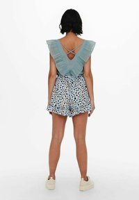 Světle modrý volánkový top s výstřihem do V a vrstveným volánem, spárovaný se světle modrými šortkami s leopardím potiskem a volánkovým lemem.