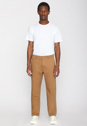 Pantaloni khaki realizzati in morbido misto cotone, con un design a gamba dritta, chiusura con bottone e due tasche laterali, indossati con una maglietta bianca semplice.