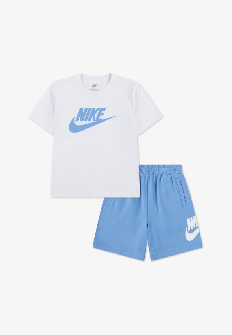 Baltas medvilnės marškinėlis su mėlynu Nike logotipu, derinamas su mėlynais šortais, kuriuose yra baltas Nike logotipas. Minkštas, kasdieniškas ir patogus dizainas.