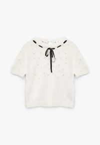 Suéter blanco de manga corta con burbujas texturizadas, cuello redondo y cinta negra en la parte posterior. Presenta un dobladillo y puños acanalados.