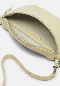 Gelbe Leder-Clutch mit Reißverschluss, Innenfutter und einem Handgelenkband. Im Inneren befindet sich eine kleine Tasche.