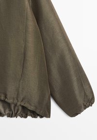 Olivově zelené texturované tričko s dlouhým rukávem a nařasenými elastickými manžetami a lemem, zobrazené na bílém pozadí.
