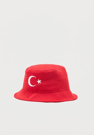Chapeau bob rouge avec un symbole blanc de croissant de lune et d'étoile sur le devant, présenté sur un fond clair uni.
