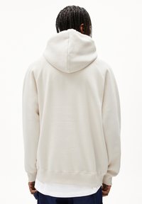 Felpa crema con cappuccio, polsini e orlo a costine, caratterizzata da una texture liscia e una vestibilità rilassata, vista da dietro.