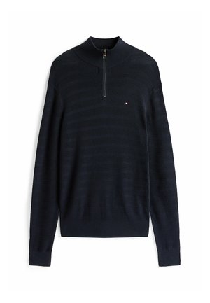 Maglione a maglia blu navy con maniche lunghe, colletto alto e zip a un quarto. Presenta una texture a coste orizzontali e un piccolo logo sul petto.