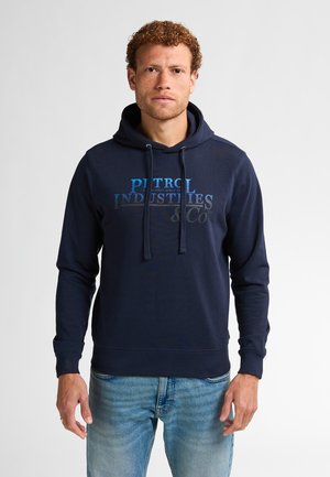Marineblauwe hoodie gemaakt van een katoenmix, met een voorprint van "Patrol Industries & Co" in verschillende tinten blauw.
