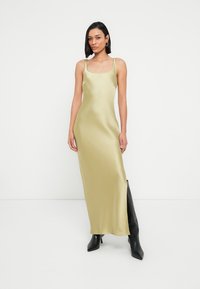 Μεταξωτό μίντι φόρεμα σε ανοιχτό πράσινο χρώμα, με τετράγωνη λαιμόκοψη και λεπτές τιράντες. Συνδυασμένο με μαύρες, ψηλές μέχρι το γόνατο, στιλέτο μπότες.