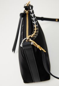 Borsa in pelle nera vista di lato con tracolla in catena oro e argento, zipper dorato e attacco per il polso in pelle.