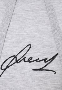 Felpa grigia in tessuto con una firma nera ricamata in evidenza. Texture liscia con dettagli a costine sui bordi.