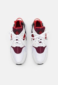 Witte en bordeaux sneakers met een bovenwerk van mesh, ronde neus, vetersluiting en opvallende branding op de tong en hiel, met een zwarte tussenzool.