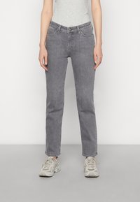 Grijze denim jeans met een recht gesneden ontwerp, vijf zakken, een knoopsluiting aan de voorkant en subtiele vervaging. Gemaakt in combinatie met lichtgekleurde sportschoenen.