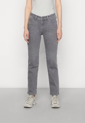 Jeans de denim gris con un diseño de pierna recta, cinco bolsillos, cierre frontal con botón y un leve desgastado. Llevados con zapatillas deportivas de color claro.